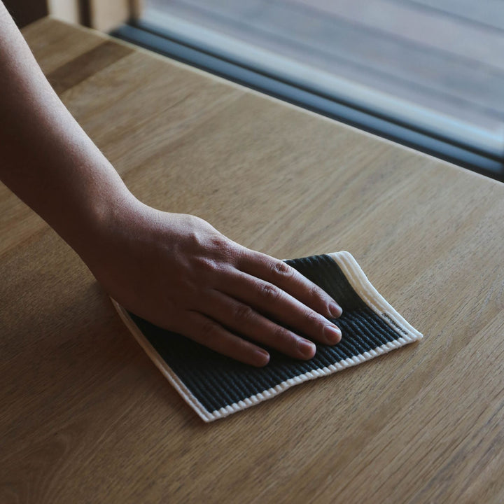Man cleaning a surface with a black dishcloth