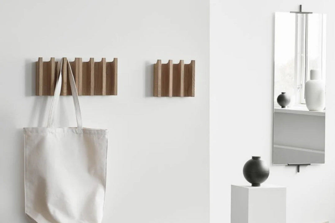 Two children standing on rust and olive sculptural stools on a green-and-cream patterned rug in a timber kitchen.