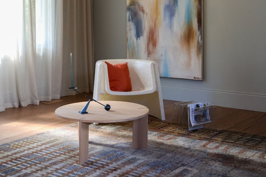 Calm living room with sculptural cream chair, terracotta cushion, abstract artwork, and soft morning light at Pointside Beaumaris.