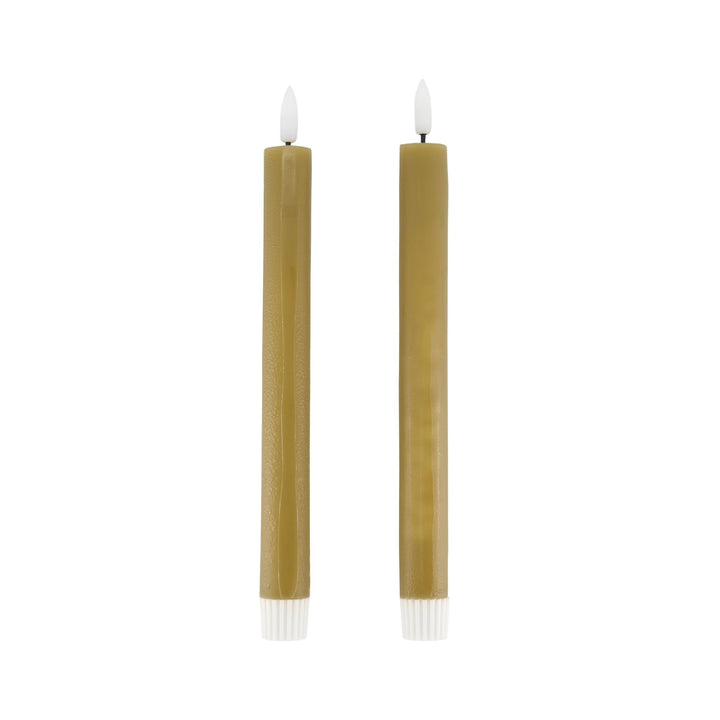 Two tall, thin candles with white wicks on a white background