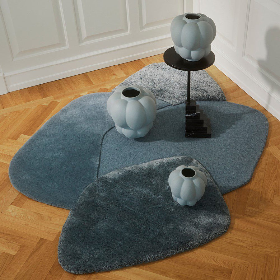 Natural lighting, top view of a rug topped with vases and a side table