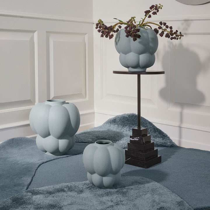 Natural lighting, perspective view of a rug topped with vases and a side table