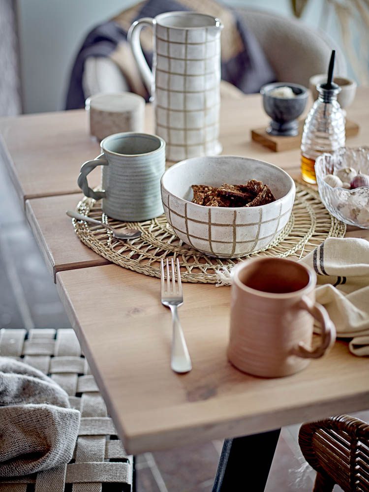 A style image of Reanna mug with a braided handle made from stoneware on a dining table.