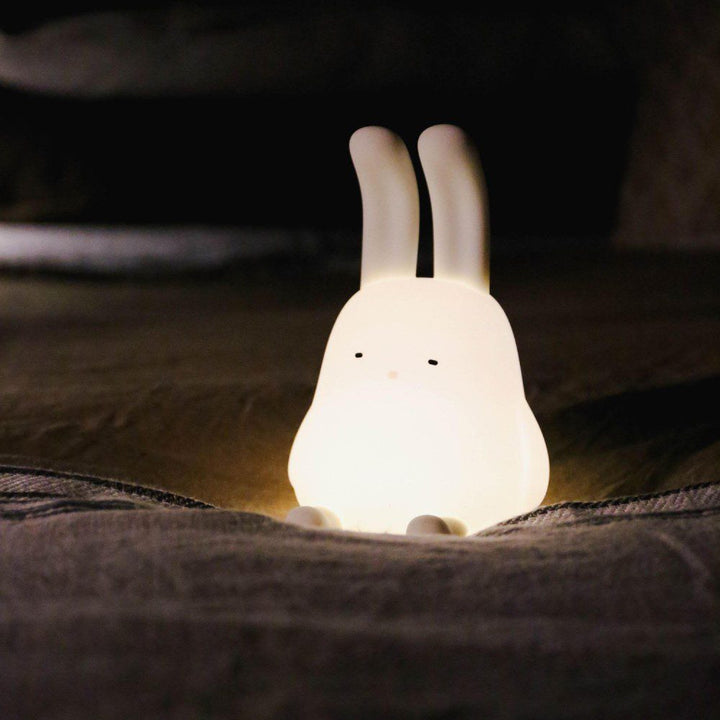 Natural lighting, perspective view of a lit kids' lamp in the shape of a rabbit.