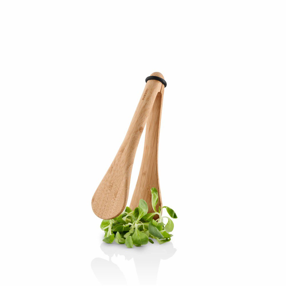 White background, studio lighting, perspective view of a wooden kitchen tong picking green leafy vegetables.