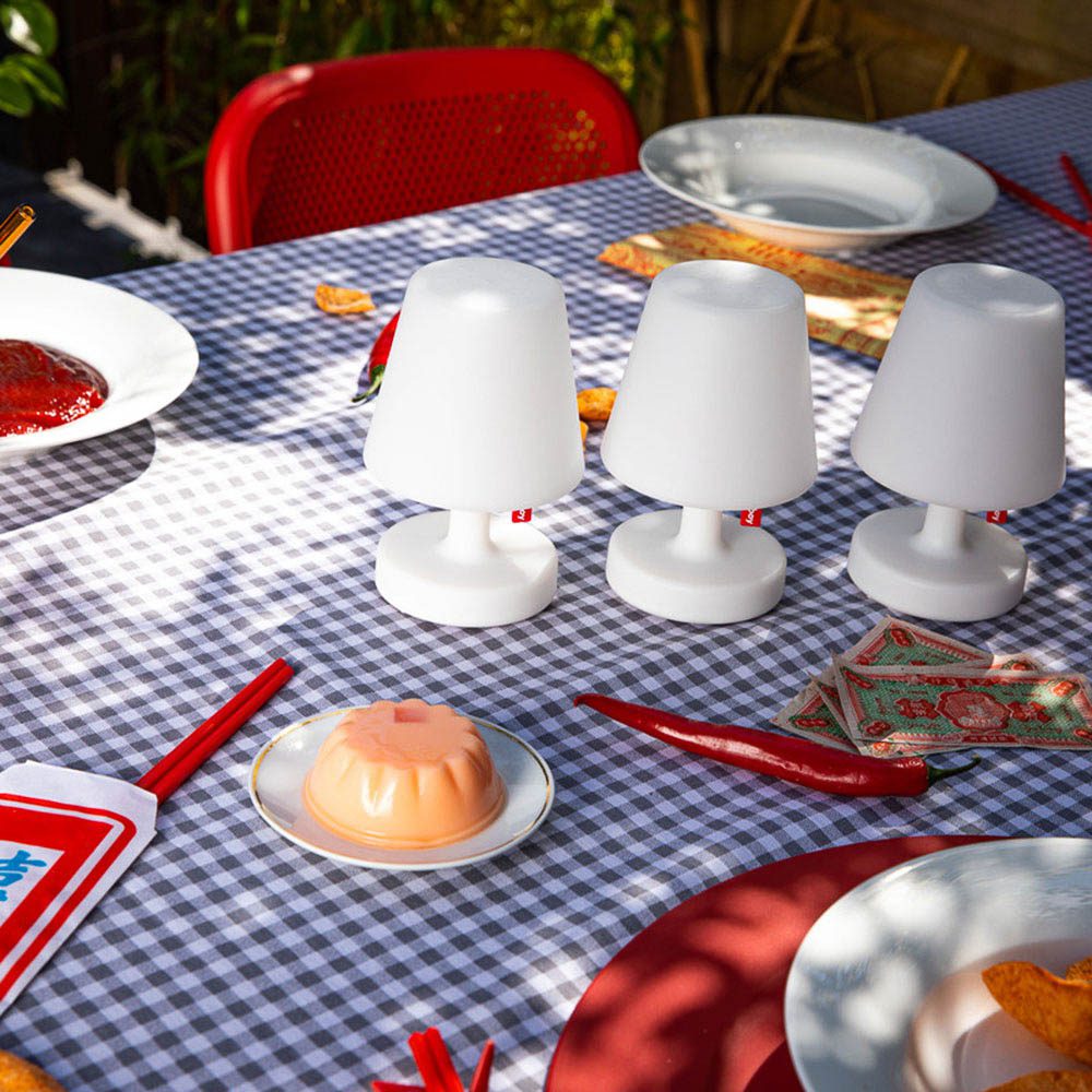 3 set of Edison the mini table lamp by Fatboy on an outdoor dining table with a blue checked tablecloth.