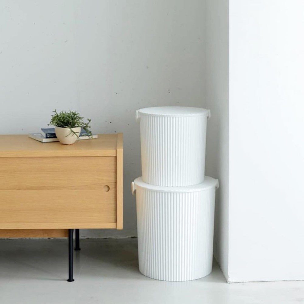 Natural light, perspective photo of a cropped cabinet, 2 white and different sized storage bins stacked on top of each other.