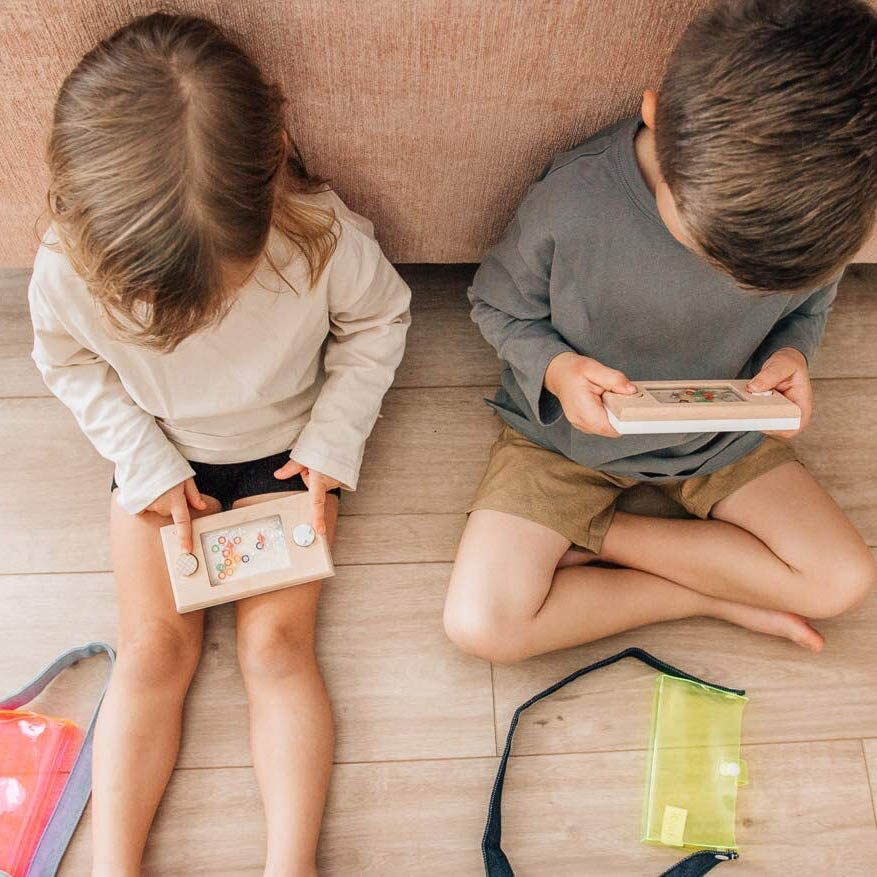 Two kids are playing vintage wooden Wakka water game on the floor.