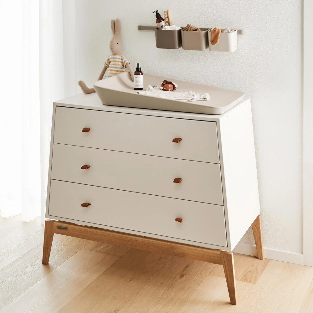 Natural light, perspective view of a white, 3-tiered wooden children's cabinet with a changing pad on top and a 3-piece organiser above it.