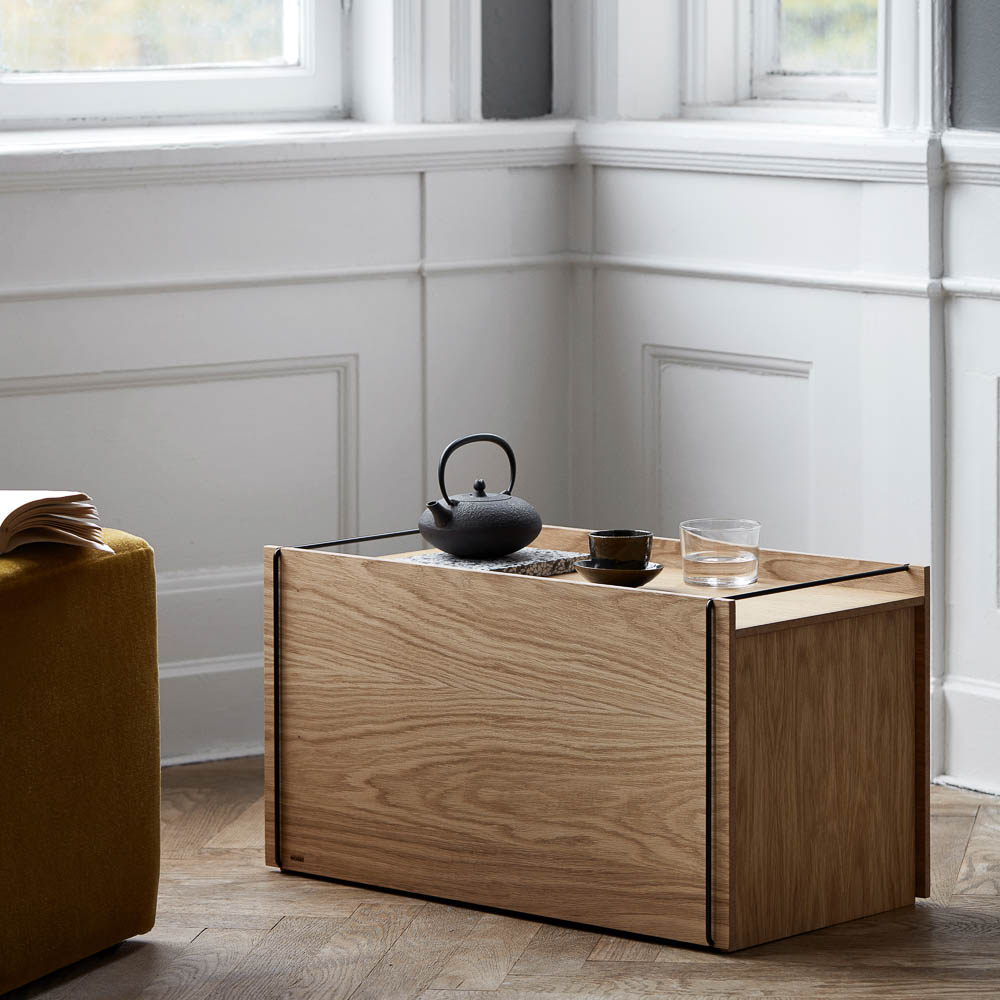 Natural light, perspective view, editorial style photo of a rectangular wooden storage box with a black teapot and cup next to it.