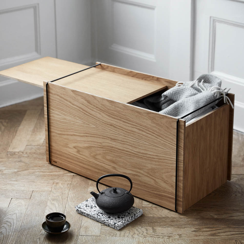 Natural light, perspective view, editorial style photo of a rectangular wooden storage box with a black teapot and cup next to it.