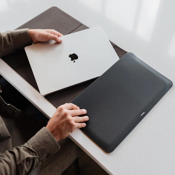 A person storing their laptop computer inside a hybrid laptop sleeve and desk mat.