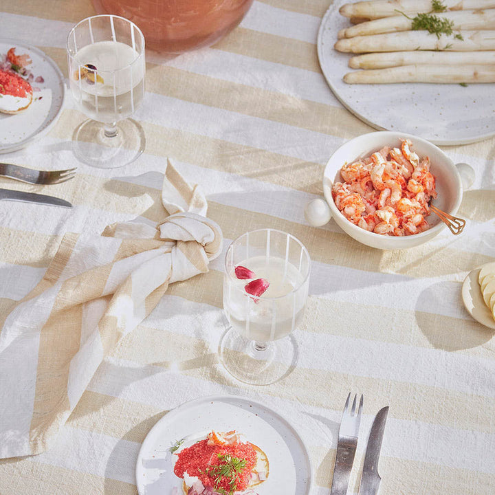 A dining table set with cotton striped napkin and tablecloth.