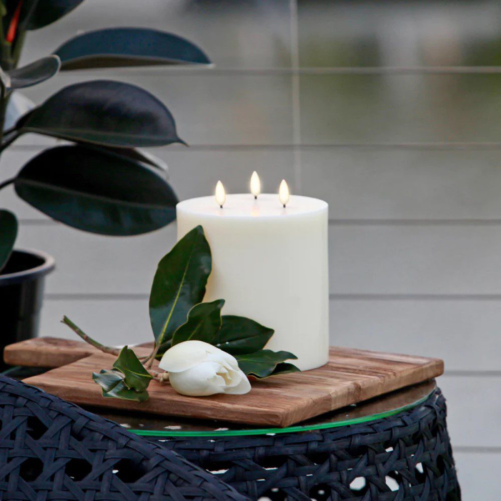 A three-wicked, flameless pillar candle placed on a table.