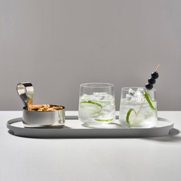 Studio image, perspective view of a filled silver-colored serving bowl beside two cocktail drinks inside a grey serving tray.